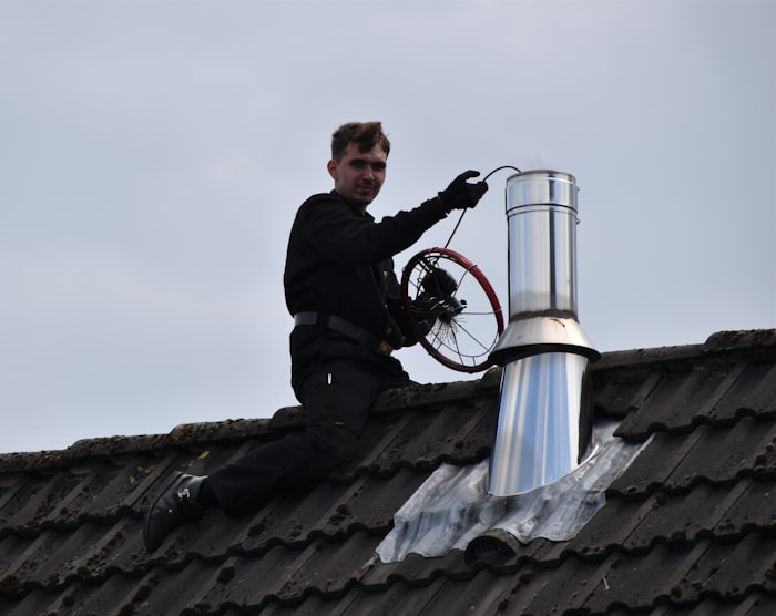 Un ramoneur passe le hérisson sur une sortie de toit